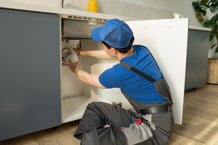 Technician installing plumbing components under a kitchen sink in Olympia, WA