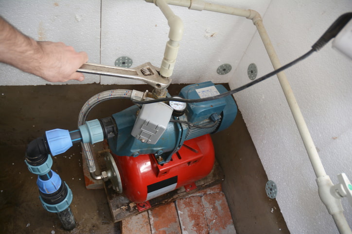 Hand tightening a wrench on a home water pump system in Olympia, WA